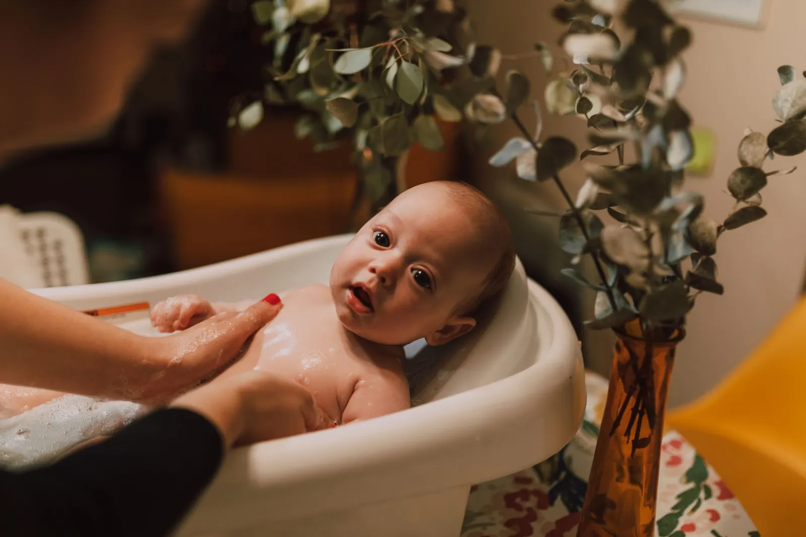 Bebé no banho, amparado por uma mão adulta