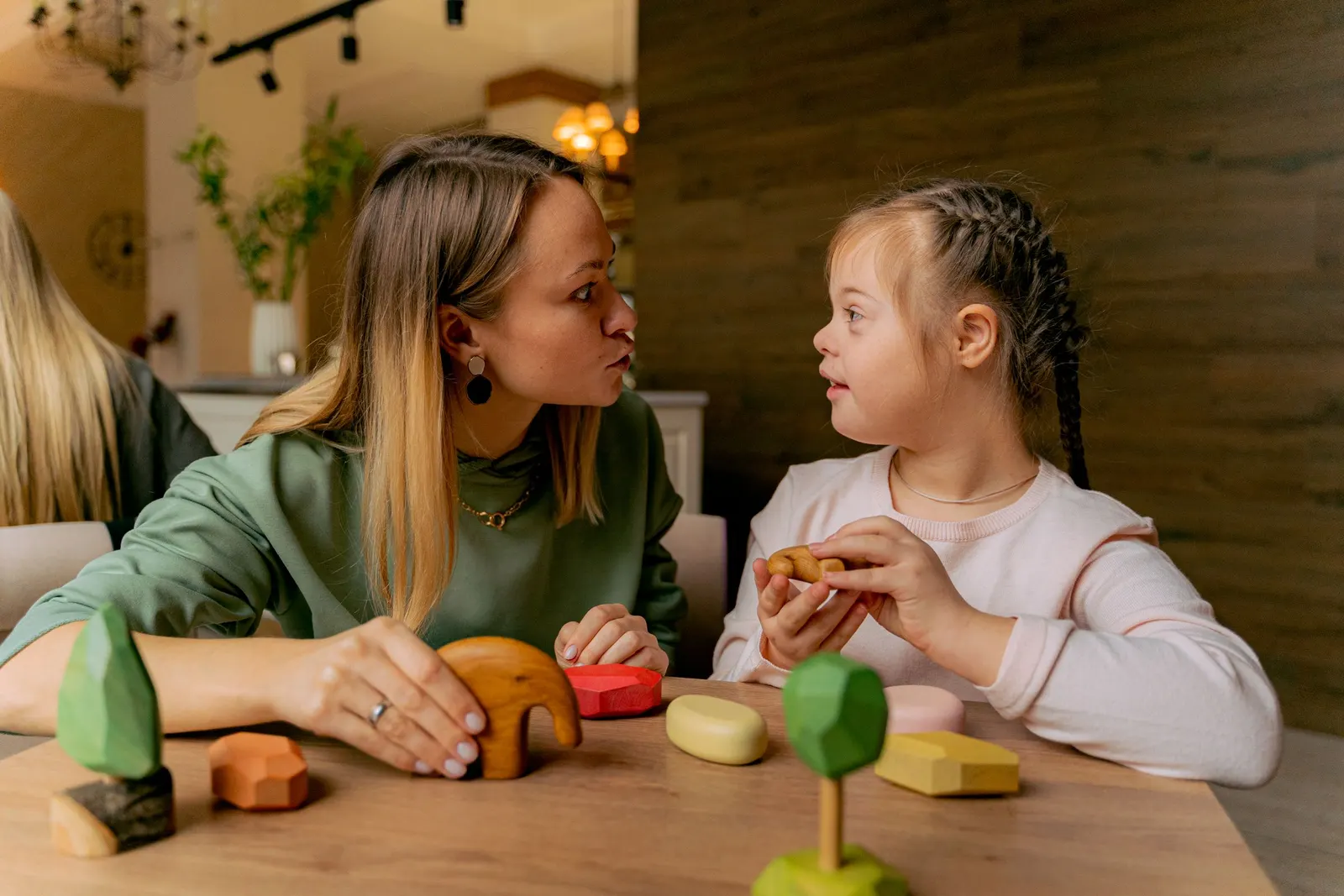 Terapeuta e menina a brincar com peças de madeira à mesa